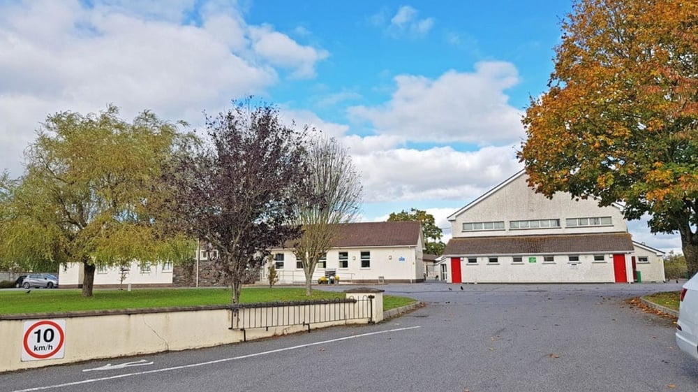 Das Wohnviertel mit herbstlich gefärbten Bäumen und einem rot gedeckten Gebäude in der Nähe der Scoil Aireagail.