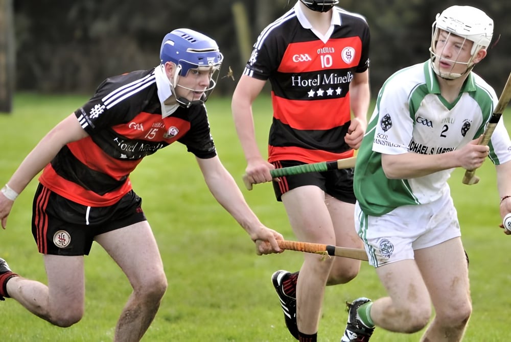 Zwei Spieler während eines Hurling-Spiels auf dem Sportplatz der Scoil Aireagail, einer versucht den Ball zu erobern.