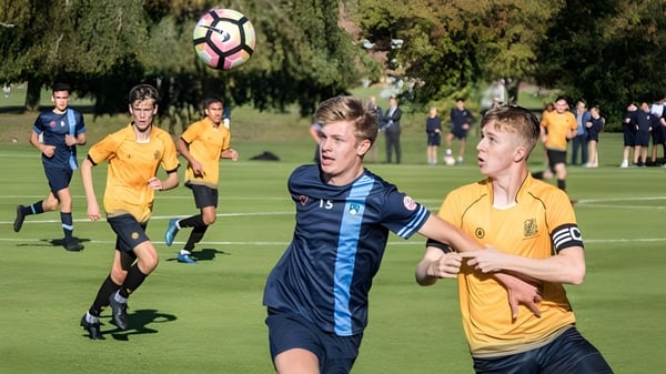 Schüler der Scoil Dara spielen ein Fußballspiel auf einem grasbewachsenen Spielfeld.