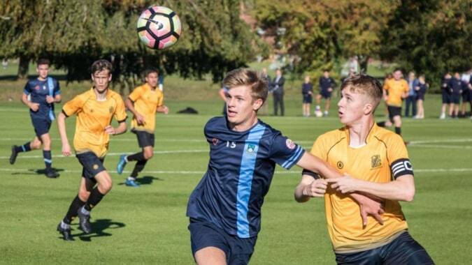 Schüler spielen ein Fußballspiel auf dem Sportplatz der Scoil Dara mit gegnerischen Mannschaften in gelben und blau-weißen Trikots.