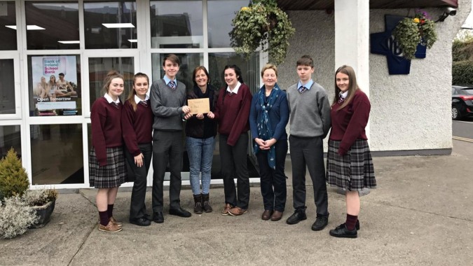 Eine Gruppe Schüler steht vor einem Gebäude auf dem Campus der Scoil Dara mit festlicher Dekoration im Hintergrund.