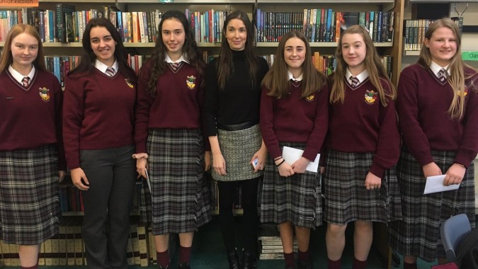 Eine Gruppe Schülerinnen in Schuluniformen steht vor einem Bücherregal auf dem Campus der Scoil Dara.