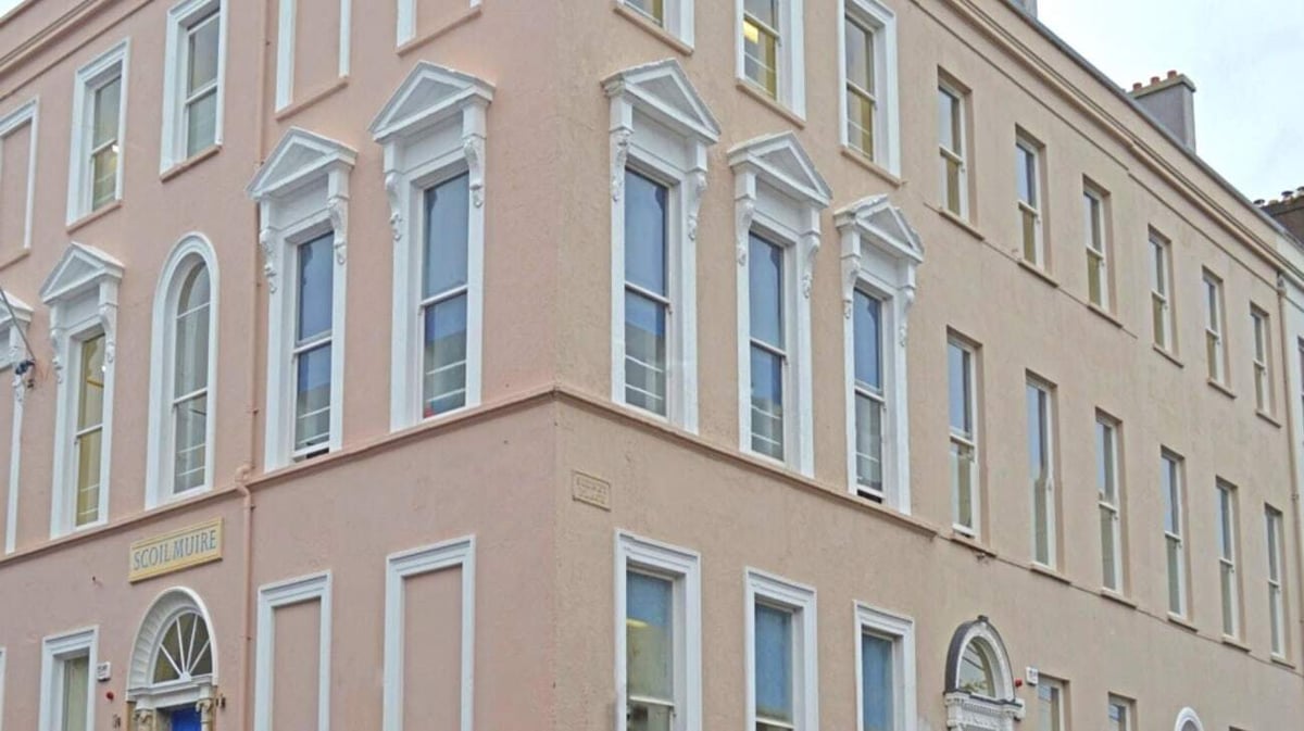 Das mehrstöckige Gebäude mit rosa Fassade und zahlreichen Fenstern gehört zur Scoil Mhuire Cork.