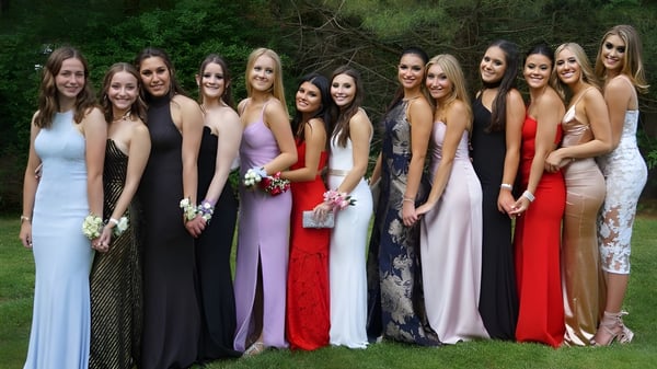 Eine Gruppe junger Frauen in formeller Kleidung steht zusammen im grünen Außenbereich der Scoil Mhuire Cork.