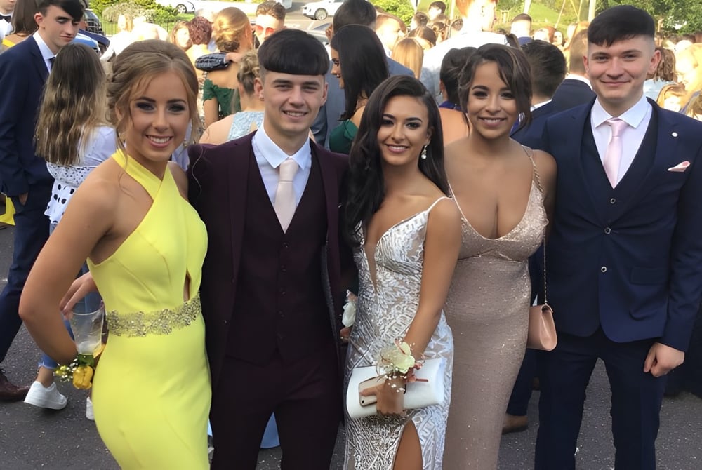 Eine Gruppe von Schülern der Scoil Mhuire gan Smál posiert gemeinsam draußen vor Gebäuden und Bäumen.