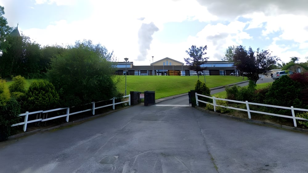 Ein gepflasterter Weg führt zu einem Gebäude auf dem Campus der Scoil Mhuire Kanturk, umgeben von Grünflächen.