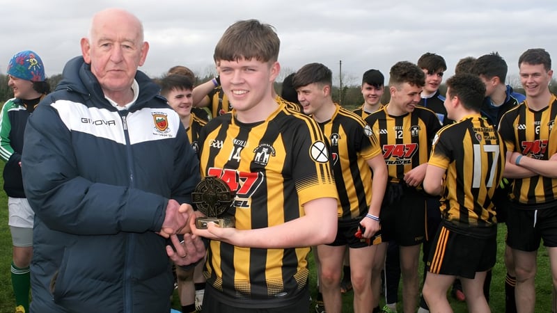 Eine Gruppe junger Fußballspieler der Scoil Mhuire (Strokestown) steht mit ihrem Trainer auf dem Fußballfeld.