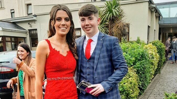 Ein junges Paar in formeller Kleidung steht vor einem Gebäude auf dem Campus der Scoil Mhuire (Strokestown).