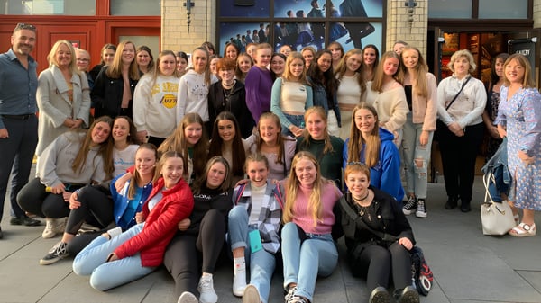 Eine Gruppe von Schülerinnen der Scoil Mhuire (Trim) posiert vor einem bunten Wandgemälde.