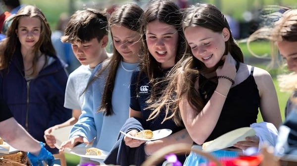 Eine Gruppe von Schülerinnen und Schülern der Scoil Ruáin unterhält sich lachend im Freien auf dem Schulgelände.