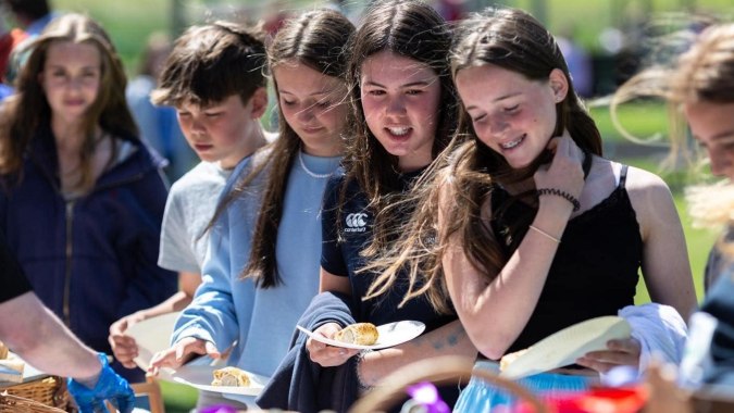 Schüler der Scoil Ruáin genießen gemeinsam eine Pause im Freien vor grünem Hintergrund.