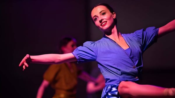 Eine Frau in blauer Kleidung tanzt auf der Bühne der Scoil Ruáin.