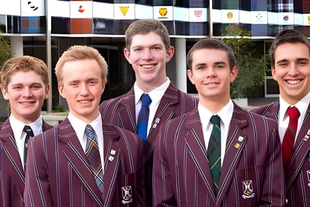 Eine Gruppe Schüler in burgunderfarbenen Schuluniformen steht vor einem Gebäude mit Fahnen auf dem Gelände des Scotch College.