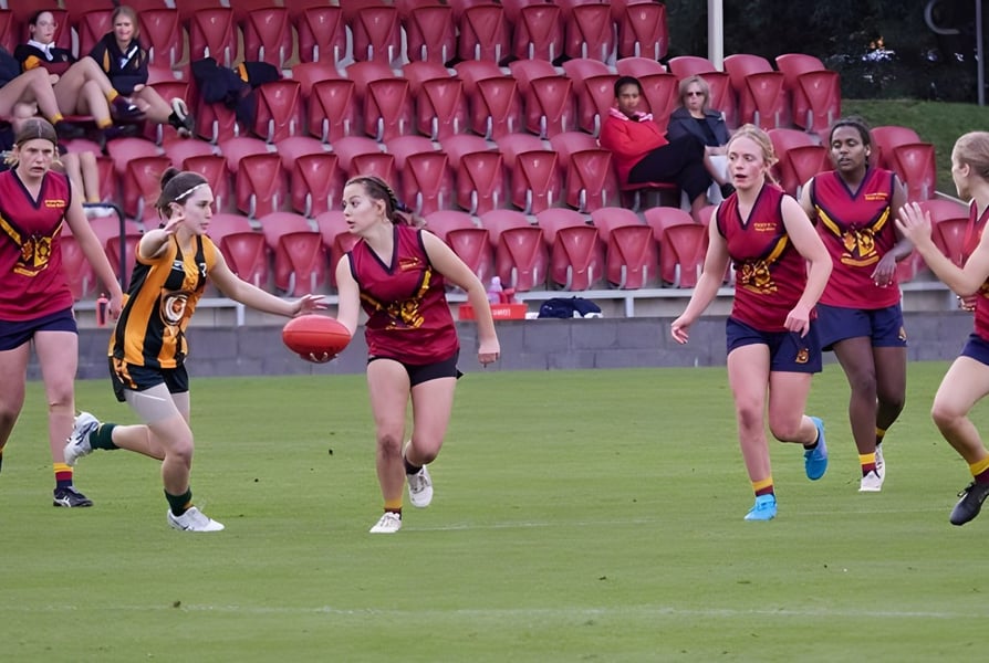 Eine Gruppe junger Sportlerinnen spielt auf dem Sportfeld des Scotch Oakburn College vor Zuschauern.