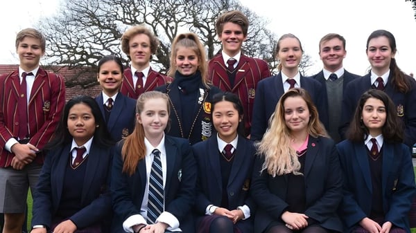 Eine Gruppe Schüler in Schuluniformen steht vor einem Backdrop aus kahlen Bäumen und einem Backsteingebäude am Scotch Oakburn College.