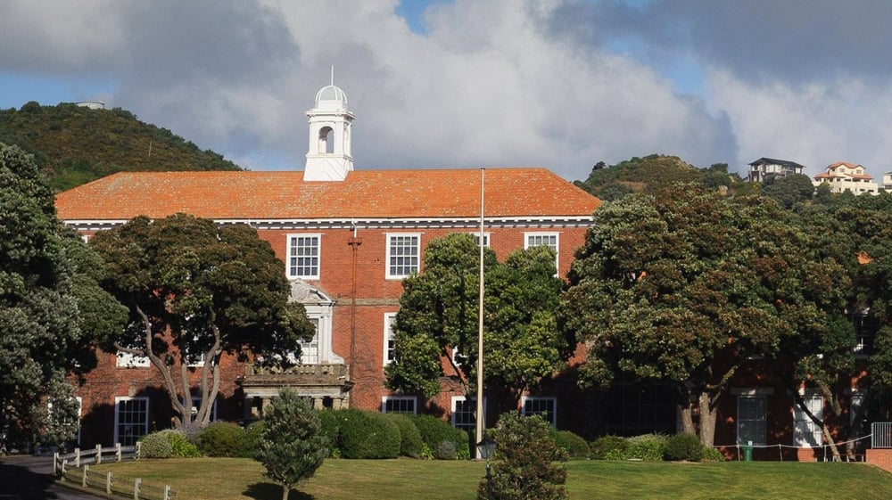 Das Backsteingebäude mit weißem Turm auf dem Campus des Scots College ist von Bäumen und Grünflächen umgeben.