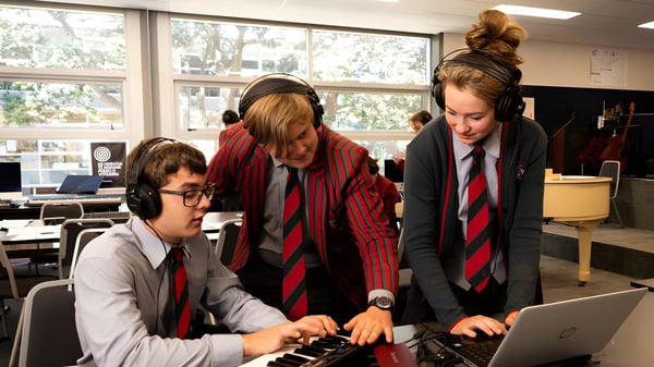 Schüler des Scots College arbeiten gemeinsam an einem Laptop in einem Klassenraum mit Ausblick ins Freie.