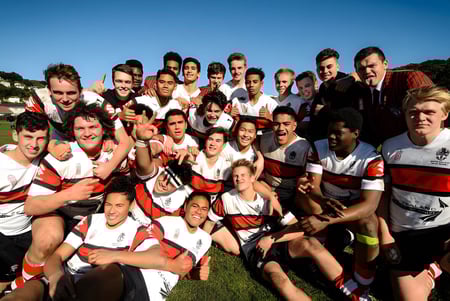 Eine Gruppe von Schülerinnen und Schülern des Scots College posiert gemeinsam auf einer grünen Wiese unter blauem Himmel.