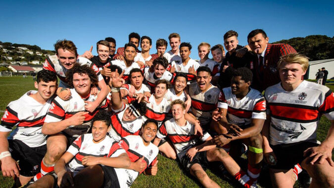 Eine Gruppe von Schülerinnen und Schülern des Scots College posiert gemeinsam als Sportteam auf einer Wiese unter blauem Himmel.