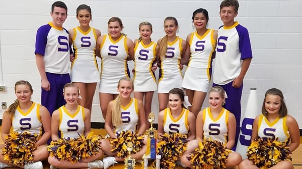 Eine Gruppe von Cheerleadern der Scottsburg High School posiert vor einer weißen Wand.