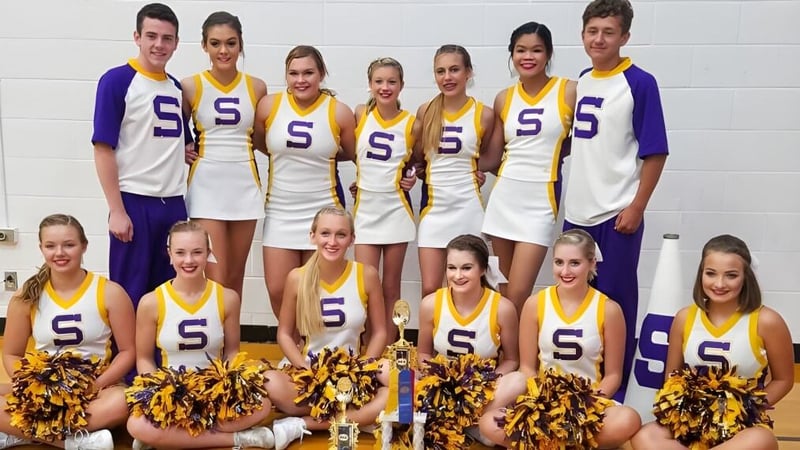 Eine Gruppe von Cheerleadern der Scottsburg High School posiert vor einer weißen Wand.