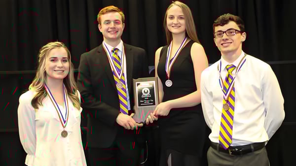 Vier Schülerinnen und Schüler der Scottsburg High School stehen gemeinsam auf einer Bühne und halten Auszeichnungen und Medaillen.