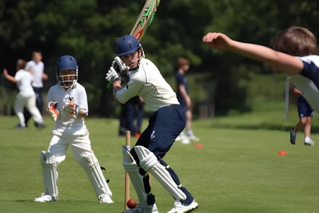 Ein Cricketspieler im weißen Trikot beim Schlagen des Balls auf dem Spielfeld des Seaford College.