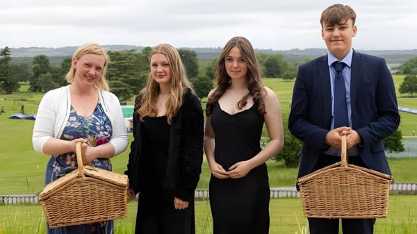 Eine Gruppe von vier Personen mit Körben steht auf dem Gelände des Seaford College vor einer Wiese mit Bäumen.