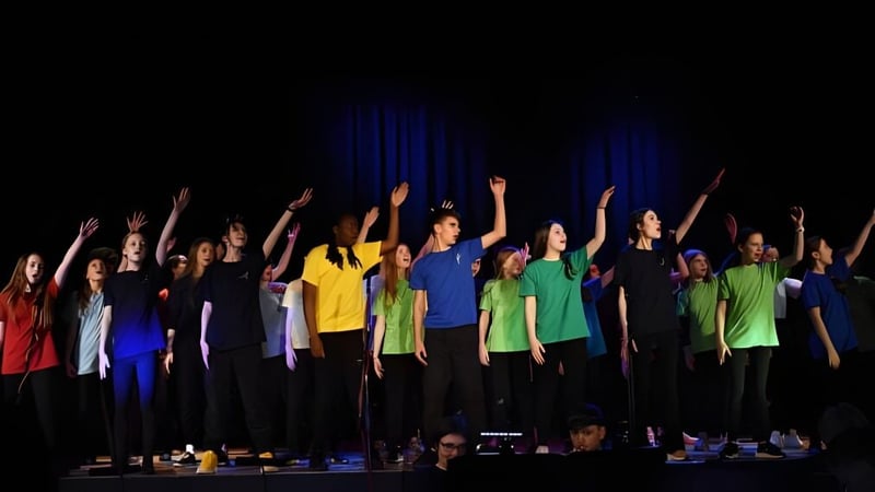 Eine Gruppe von Schülerinnen und Schülern der Seaford Head School steht auf der Bühne und hebt die Arme jubelnd.