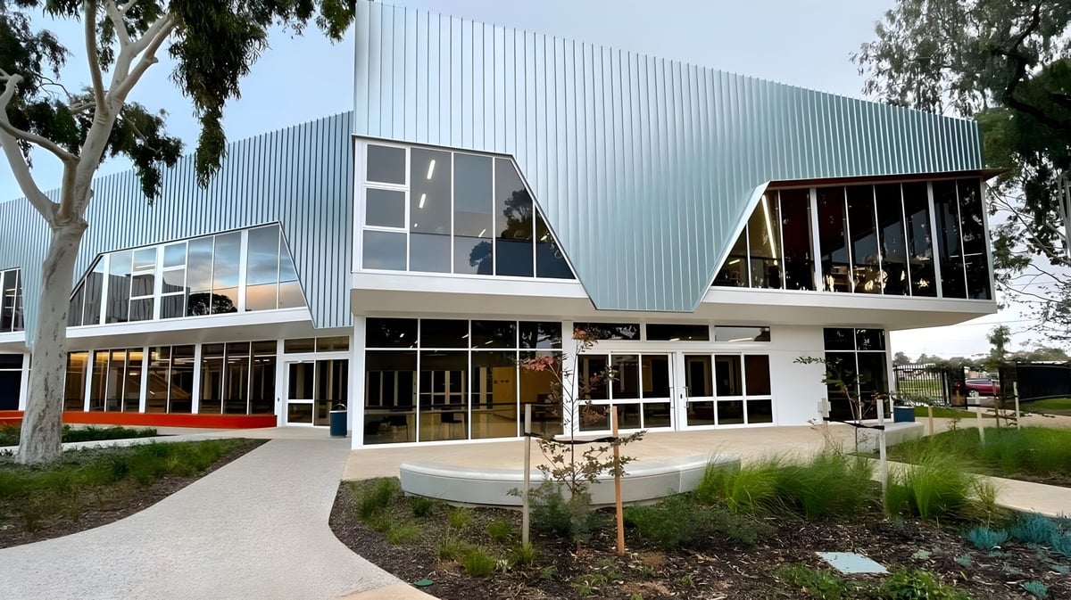 Das moderne Gebäude der Seaton High School mit großen Glasfenstern und einem gepflasterten Weg, umgeben von Bäumen.