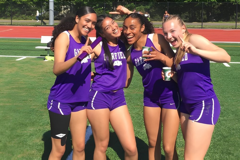 Eine Gruppe von Schülerinnen in lila Uniformen posiert auf dem Sportplatz der Seattle Public Schools für ein Foto.
