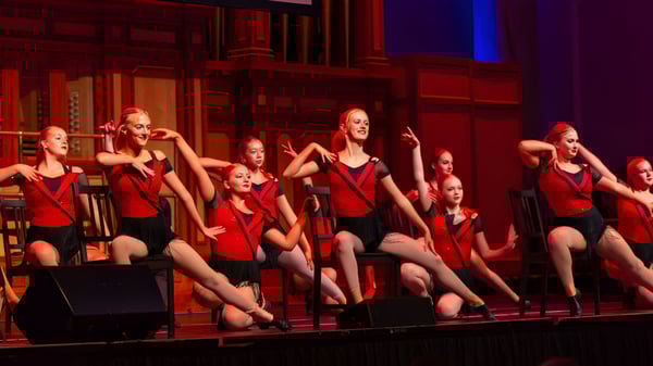 Eine Gruppe junger Tänzerinnen der Seaview High School führt auf einer Bühne mit roter und blauer Beleuchtung auf.