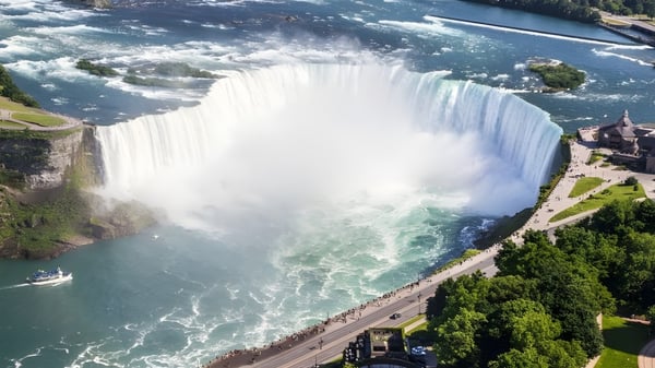 Ein Wasserfall fließt über eine Felsklippe mit grüner Umgebung und einem Fluss im Hintergrund nahe der Seaway District High School.