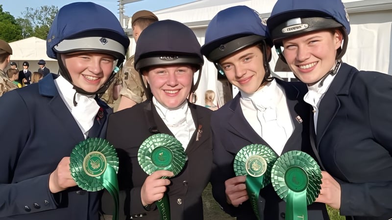 Vier Männer in formeller Kleidung mit Reithelmen halten grüne Rosetten bei einem Event auf dem Gelände der Sedbergh School.