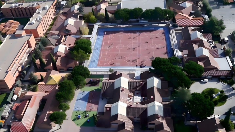 Luftaufnahme der SEK International School El Castillo mit dem großen, rotgedeckten Hauptgebäude und umliegenden Wohnhäusern.