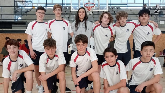 Eine Gruppe Schülerinnen und Schüler der SEK International School Catalunya posiert in der Sporthalle vor einem Basketballkorb.