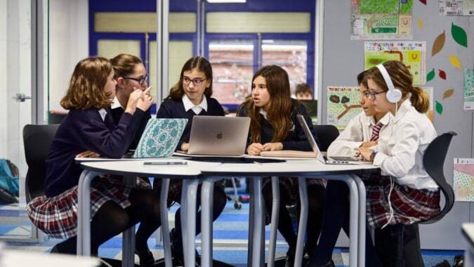 Eine Gruppe weiblicher Schüler diskutiert gemeinsam mit einem Laptop im Klassenraum der SEK International School El Castillo.