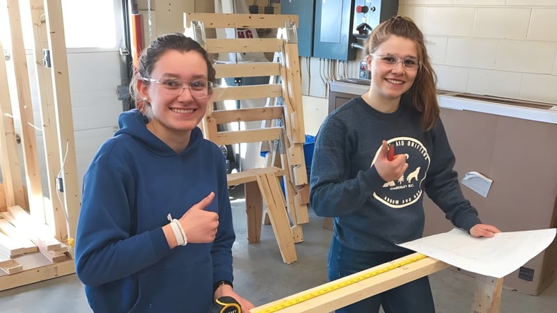 Zwei Schülerinnen der Selkirk Secondary School arbeiten gemeinsam in einer Werkstatt an einem kreativen Projekt.