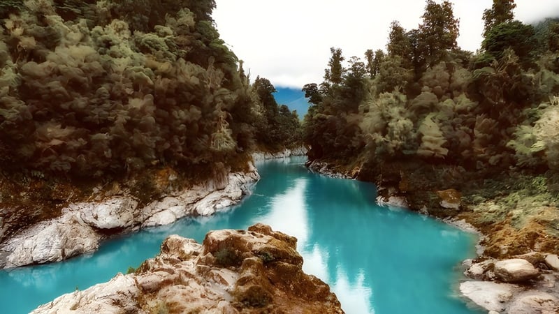 Ein türkisfarbener Fluss fließt durch einen bewaldeten Canyon mit hohen Felsen in der Nähe von Selwyn College.