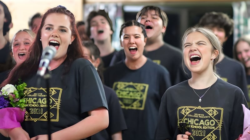 Eine Gruppe Schülerinnen und Schüler des Selwyn College singt gemeinsam mit schwarzer Chicago-T-Shirts bekleidet.
