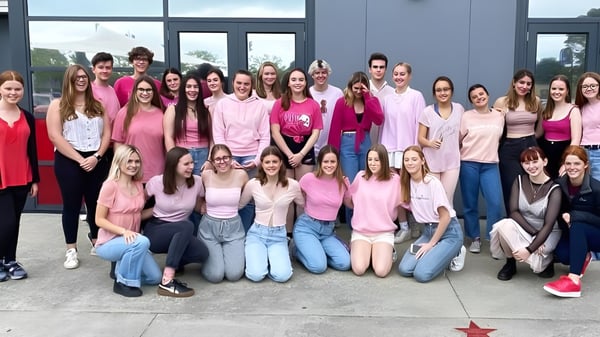 Eine Gruppe junger Frauen in verschiedenen Pinktönen posiert vor einem modernen Gebäude auf dem Selwyn College.