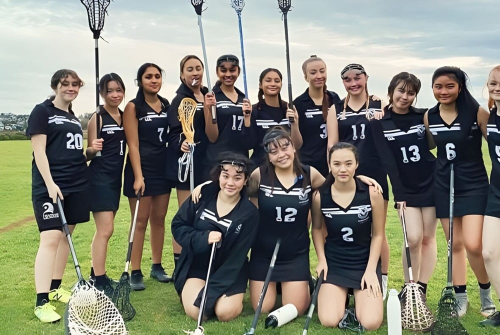 Eine Gruppe von Schülerinnen in schwarzen Schuluniformen posiert auf einem Spielfeld auf dem Campus des Selwyn College.