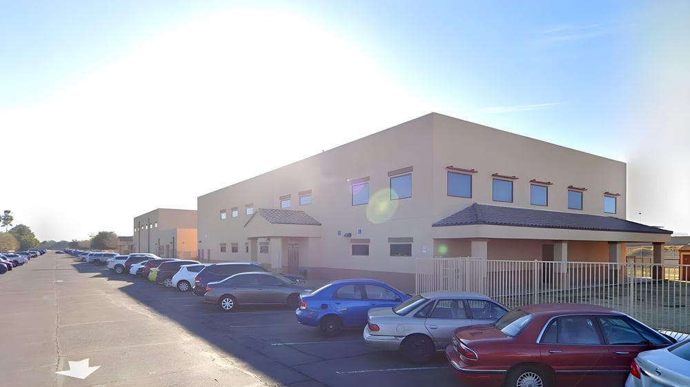 Das mehrstöckige Schulgebäude der Sequoia Charter High School mit dem Parkplatz und geparkten Autos im Vordergrund.