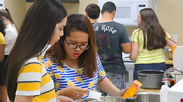 Eine Gruppe Schüler der Sequoia Charter High School ist in der Küche bei verschiedenen Tätigkeiten versammelt.
