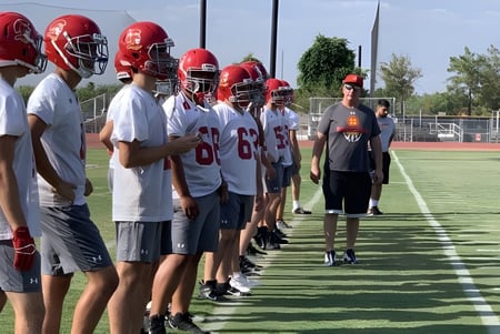 Eine Gruppe junger Footballspieler trainiert mit ihrem Coach auf dem Sportplatz der Seton Catholic High School.