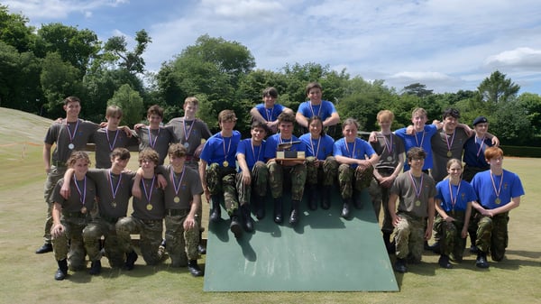 Eine Gruppe von Schülerinnen und Schülern der Sevenoaks School steht auf einer Wiese mit Bäumen im Hintergrund.