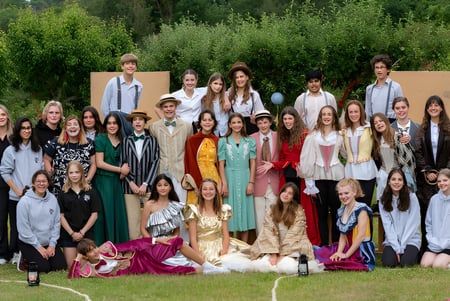 Eine Gruppe von Schülerinnen und Schülern der Sevenoaks School steht draußen vor grüner Landschaft.