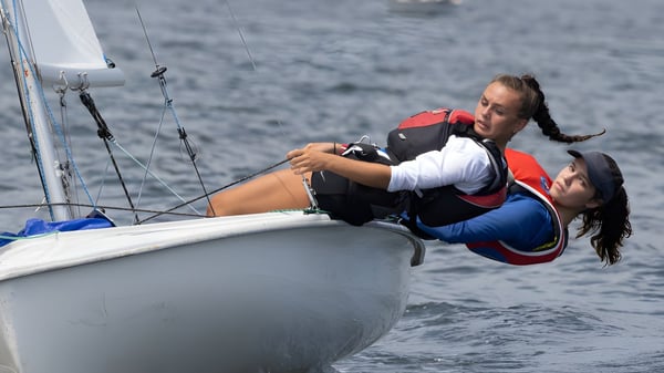 Zwei Personen segeln mit einem kleinen Boot auf dem Wasser im Hintergrund der Sevenoaks School.