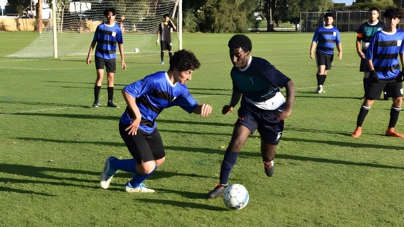 Eine Gruppe von Fußballspielern in blau-schwarzer Uniform spielt ein Spiel auf dem Sportplatz des Sevenoaks Senior College.
