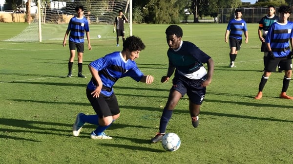 Eine Gruppe von Fußballspielern in blau-schwarzer Uniform spielt ein Spiel auf dem Sportplatz des Sevenoaks Senior College.